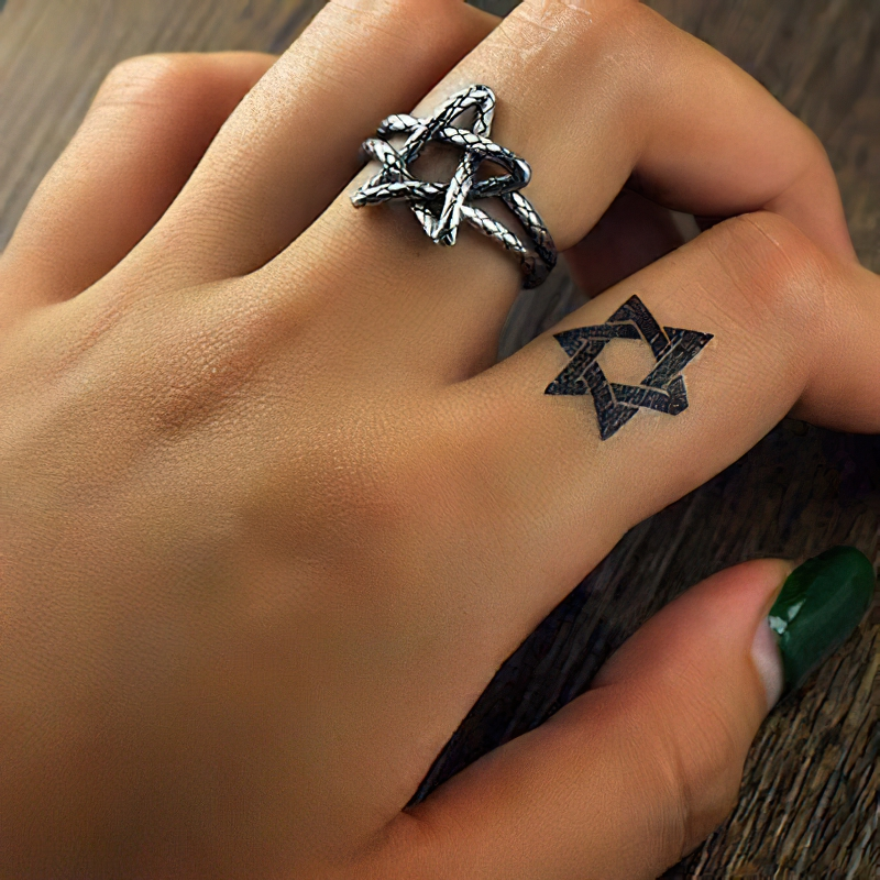 Stylish hand showcasing a Five Star Open Ring and a star tattoo, blending modern jewelry with unique body art.