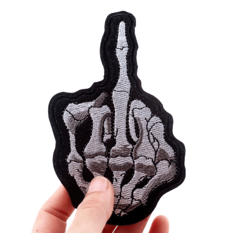Unisex gothic style "Flip Off" bone hand patch being held for clothes decoration.