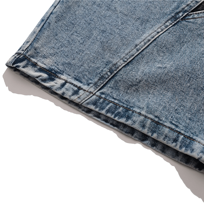 Detail of loose denim shorts for men showcasing stylish patchwork design and frayed hem.