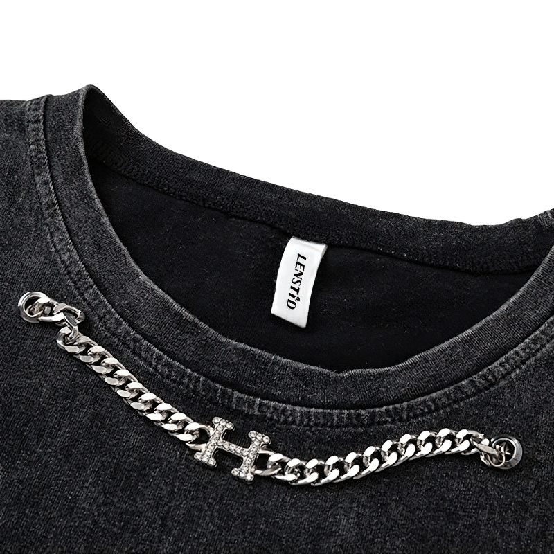 Close-up of a black gothic tank top with a silver chain accessory and printed label.