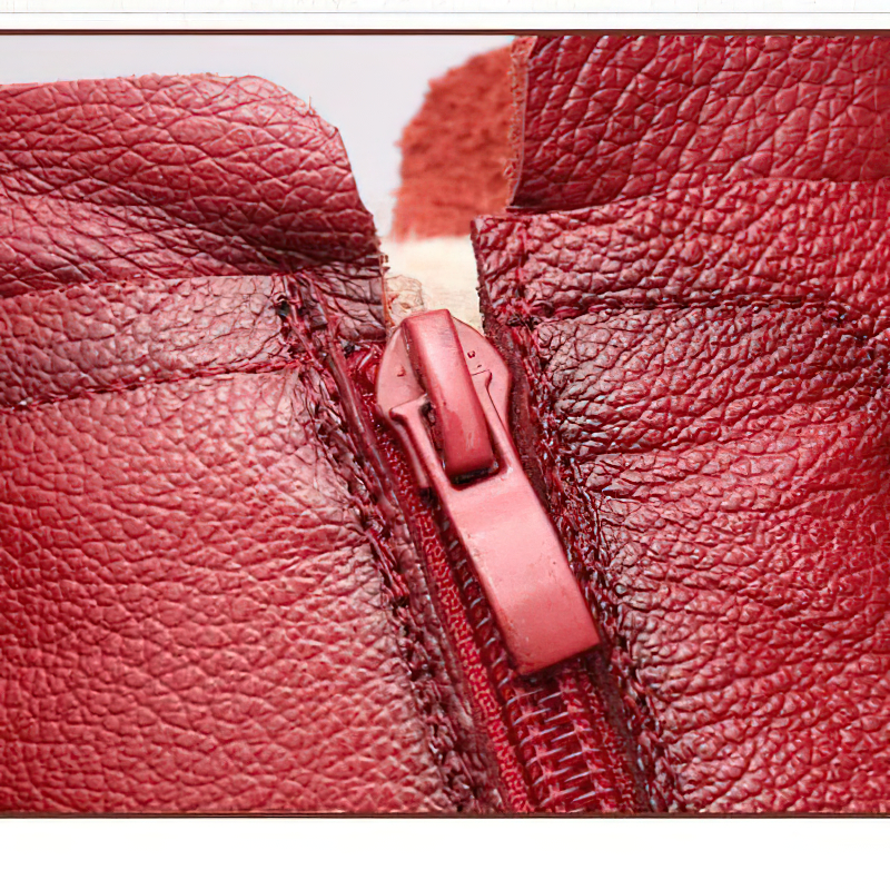 Close-up of the zipper on genuine leather ankle boots in rich red, showcasing quality craftsmanship and stylish design.