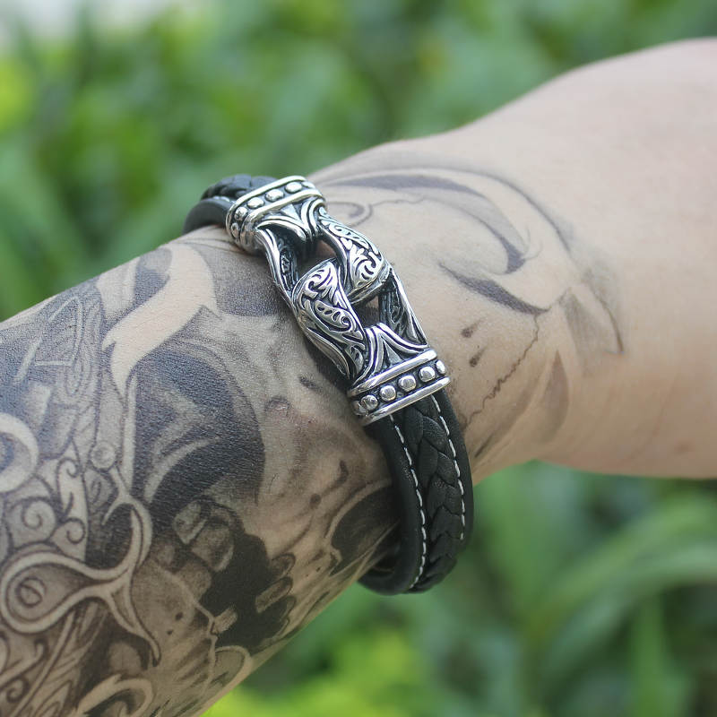 Genuine leather and stainless steel gothic bracelet worn on tattooed wrist, perfect for edgy fashion styles.