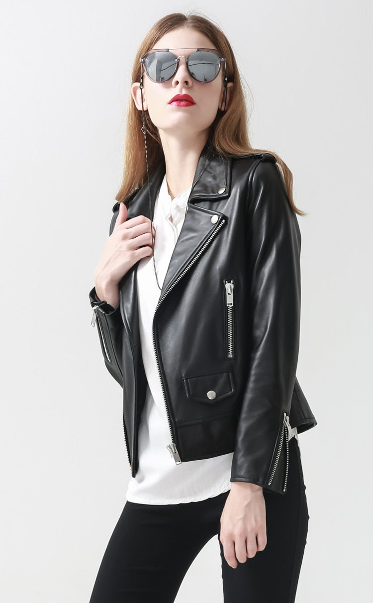 Stylish woman in a black genuine leather motorcycle jacket with sunglasses, showcasing rock chic fashion.