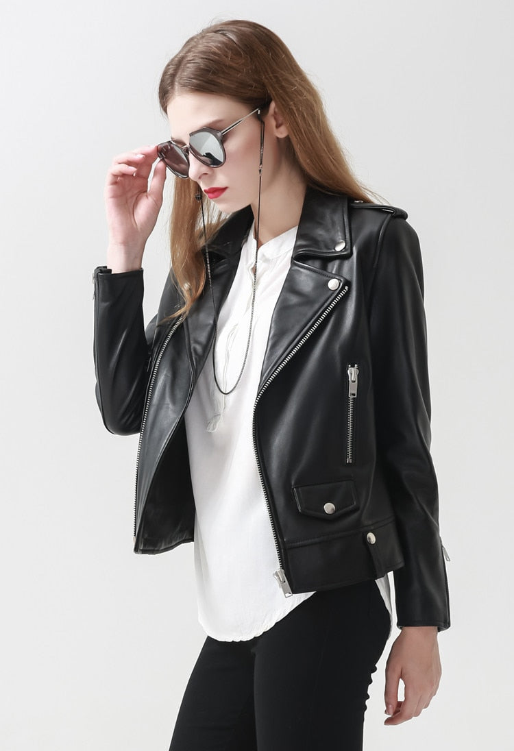 Stylish woman in a black leather motorcycle jacket, sunglasses, rocking a chic goth look.