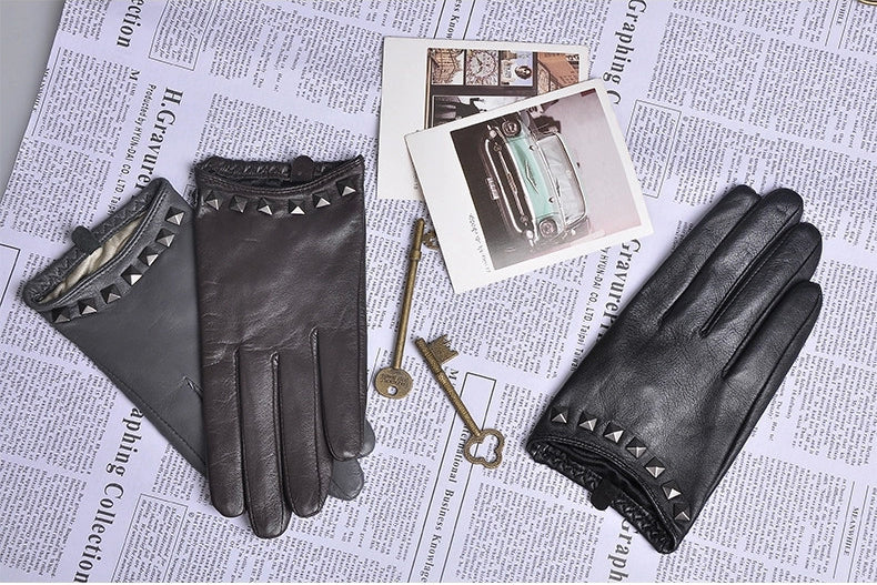 Genuine leather women's gloves with wrist rivets, stylish sheepskin design on a vintage newspaper backdrop.