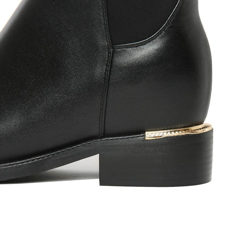Close-up of genuine leather knee-high women's boots with a stylish gold-accented square heel.