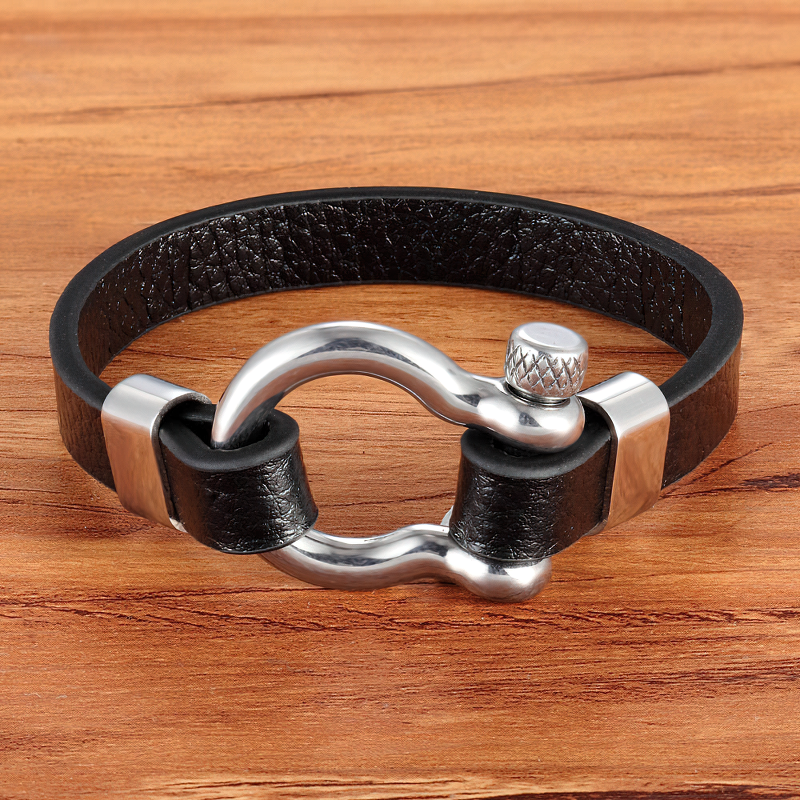 Geometric circle toggle-clasps genuine leather bracelet with stainless steel accents on wooden surface.