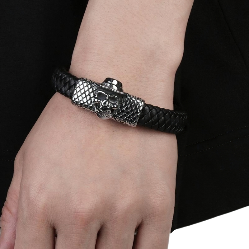 Glamour men's leather skull bracelet on wrist, featuring stylish silver skull charm and trendy woven design.
