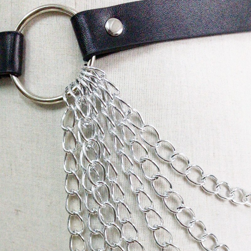 Close-up of a gothic leather chain body harness belt with silver metal chains and adjustable buckle.