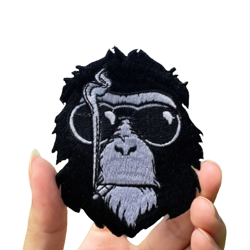 Stylish goth patch of a gorilla in glasses with a cigar held in hand, unisex clothing accessory.