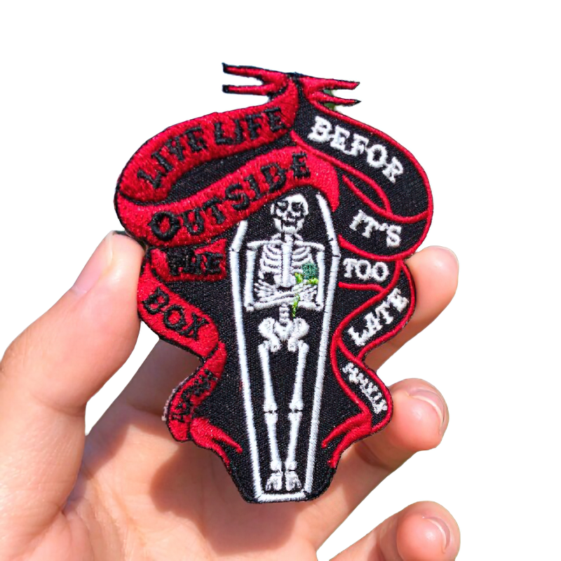 Gothic style unisex patch featuring a skeleton in a coffin with bold text, perfect for adding edge to your clothing.