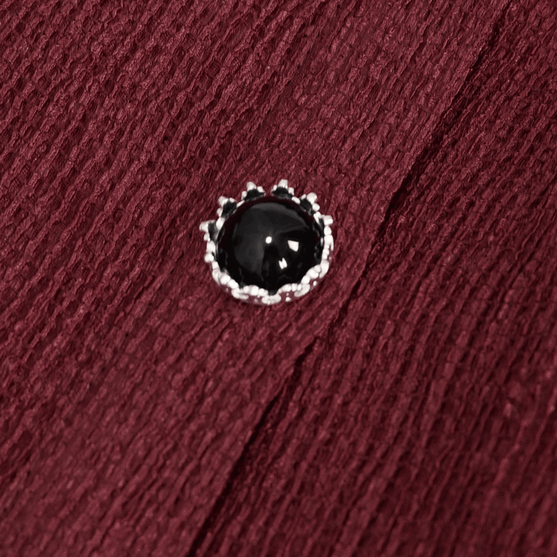 Close-up of a silver button with a black stone on a wine-red textured blouse, highlighting gothic fashion details.