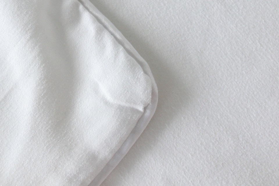 Close-up of soft white bedding fabric showcasing smooth texture and stitching details.
