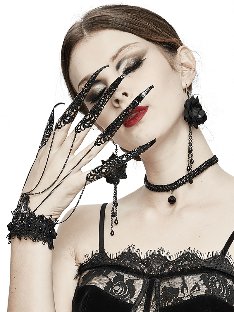 Gothic black bracelet with finger cover and chains, worn by a model with dramatic makeup and lace attire.