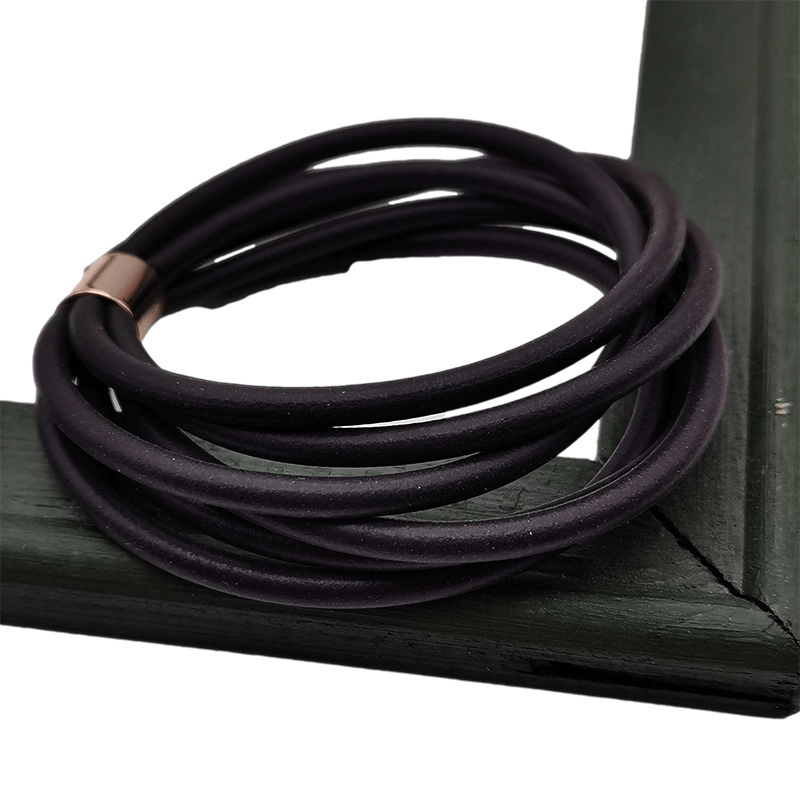 Gothic black rubber bangles stacked on a dark green frame, stylish vintage charm for women's gothic outfits.