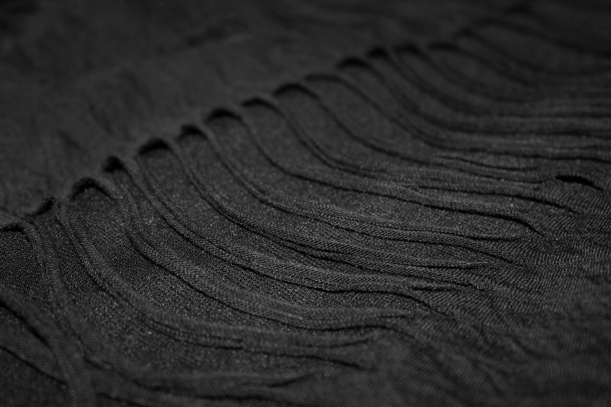 Close-up of black fringed fabric, showcasing the stylish details of a gothic men's T-shirt.