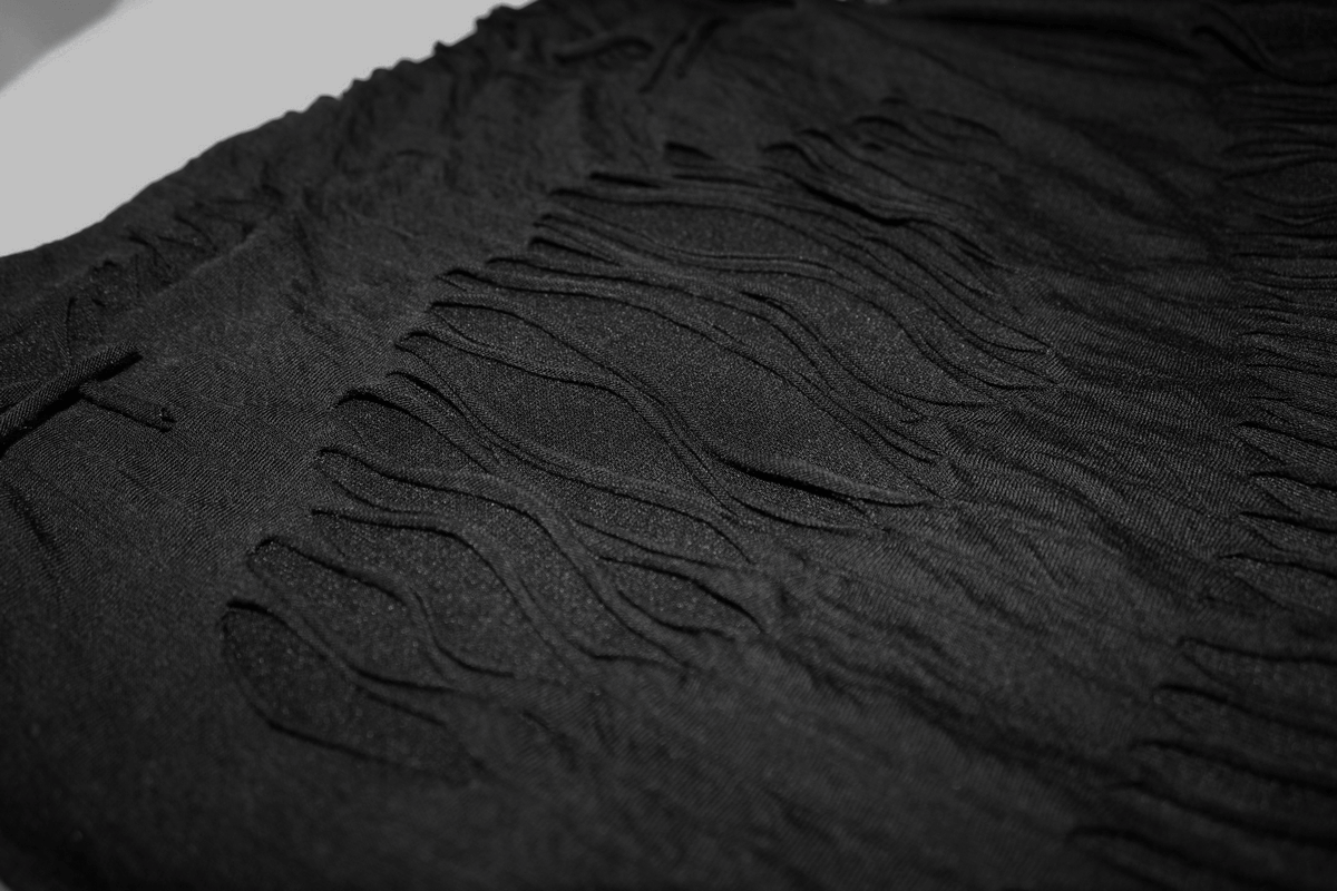 Close-up of gothic black t-shirt fabric featuring stylish slashes and fringes for a trendy look.