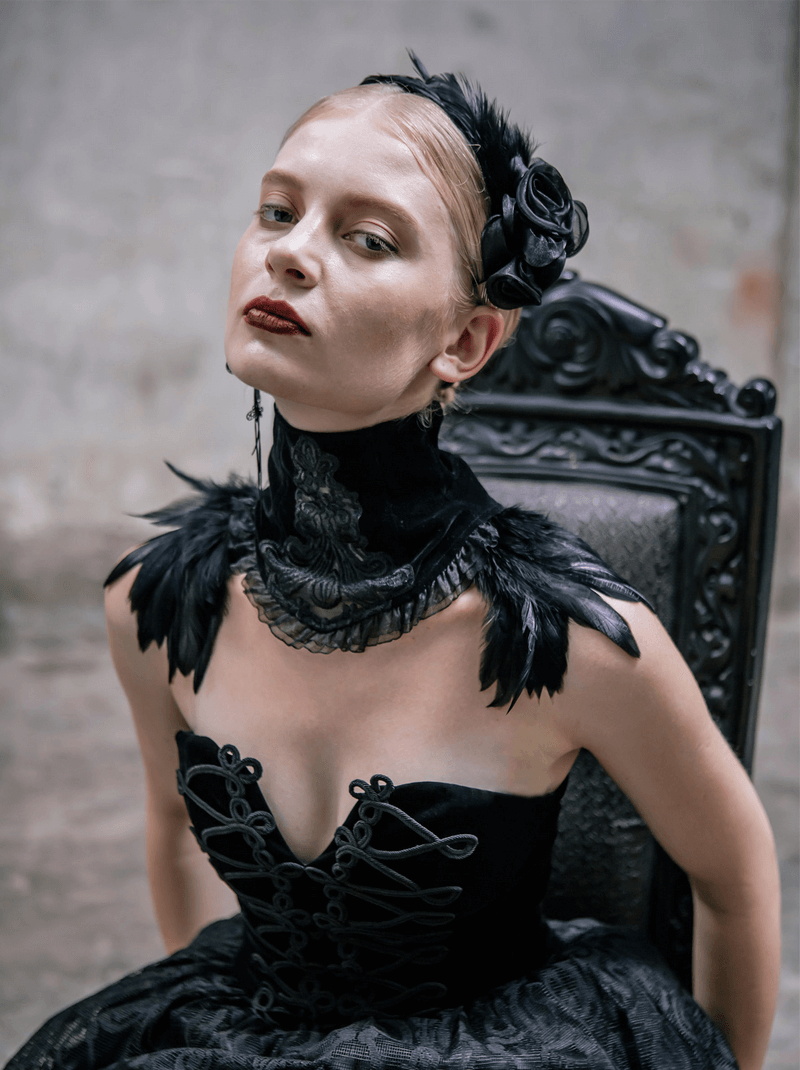 Elegant model wearing a black velvet lace choker with feathers, showcasing gothic fashion style against a vintage chair.