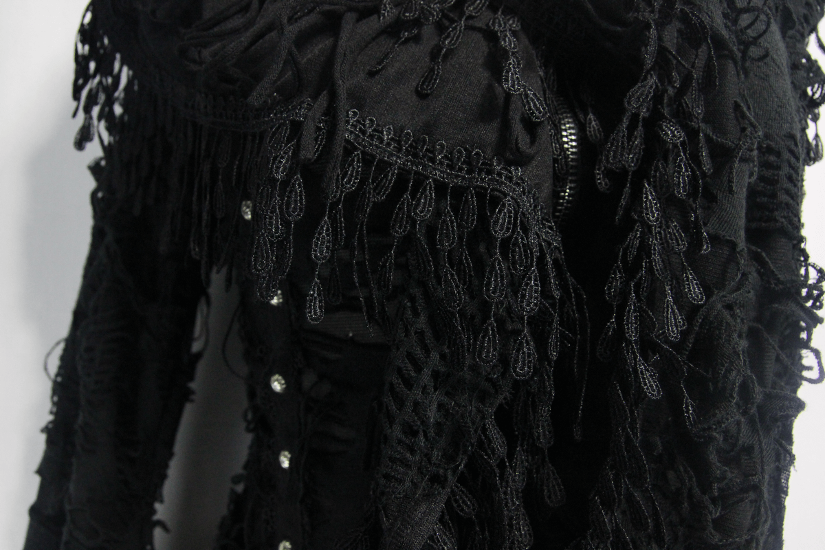 Close-up of a black gothic coat with intricate fringe design and decorative buttons, perfect for a steampunk wardrobe.