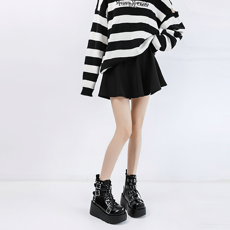 Stylish woman wearing striped sweater and black skirt with Gothic buckles platform ankle boots.
