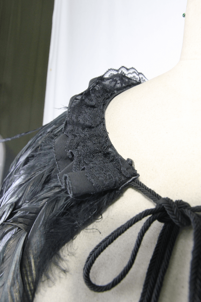 Close-up of gothic crow feather shoulder accessory showcasing lace and drawstring details.