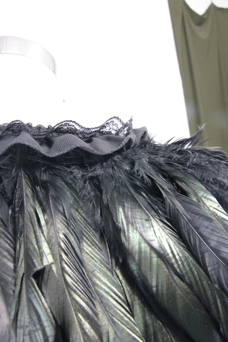 Close-up of a gothic crow feather shoulder accessory with lace trim, perfect for a stylish steampunk look.