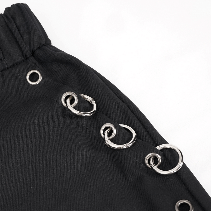 Close-up of black cargo pants featuring silver hoop accents and elastic waistband for a punk fashion flair.