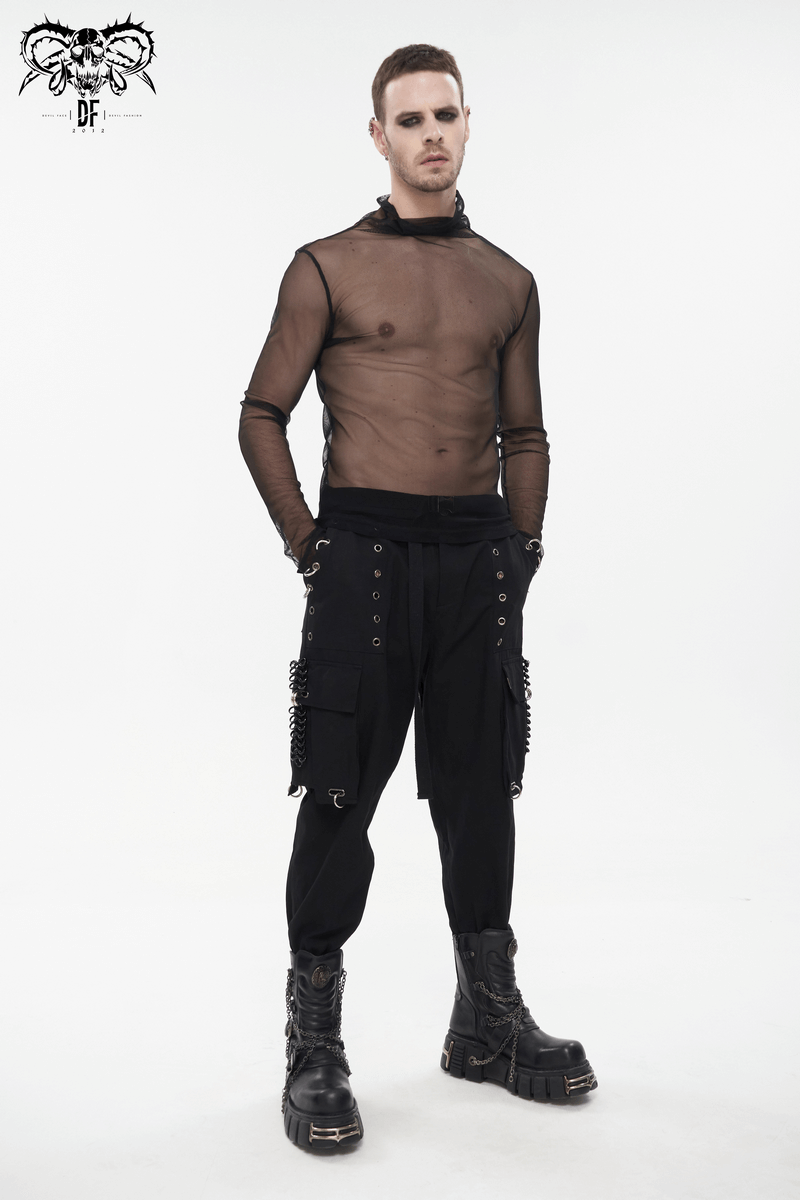 Punk male model in sheer top and black cargo pants with rivets and hoop accents, styled with chunky boots.