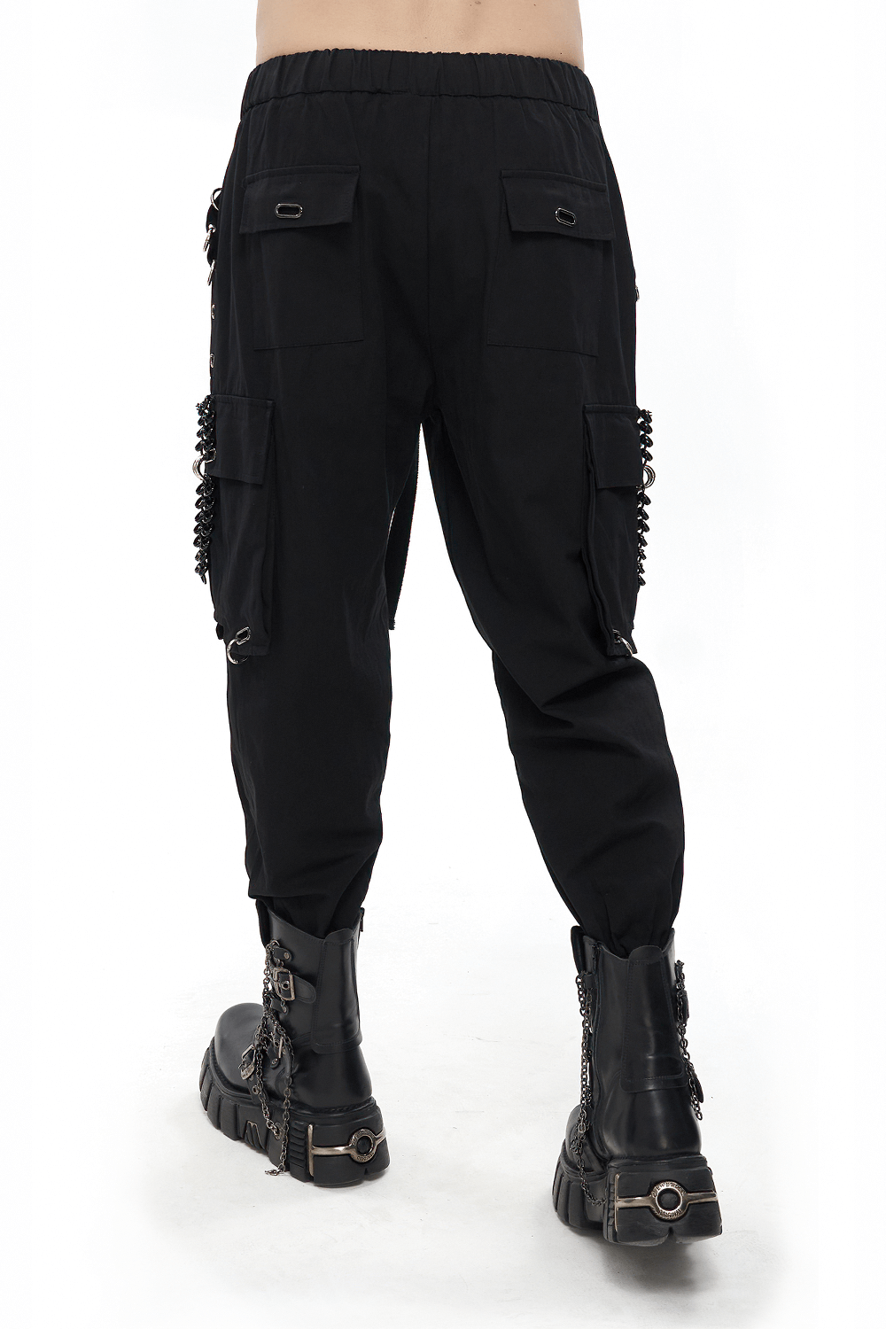 Back view of black gothic elastic waistband tapered trousers with rivets and hoop accents, styled with heavy boots.