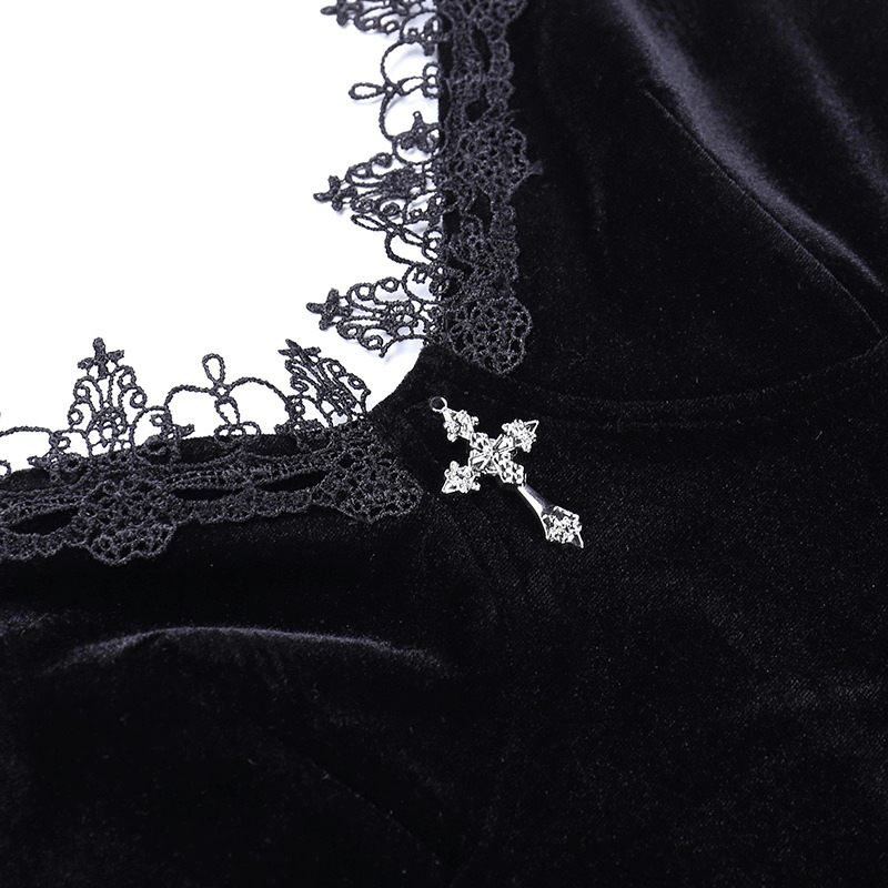 Close-up of black velvet dress detailing with lace trim and silver cross embellishment, showcasing gothic elegance.