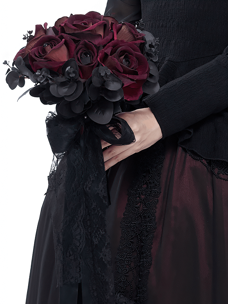 Gothic flower bouquet featuring deep red roses and black accents, elegantly held by a stylishly dressed woman.