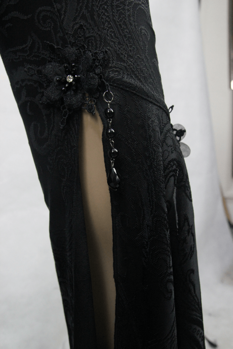 Close-up of gothic black bell-bottom pants showcasing side slits and decorative pendants.