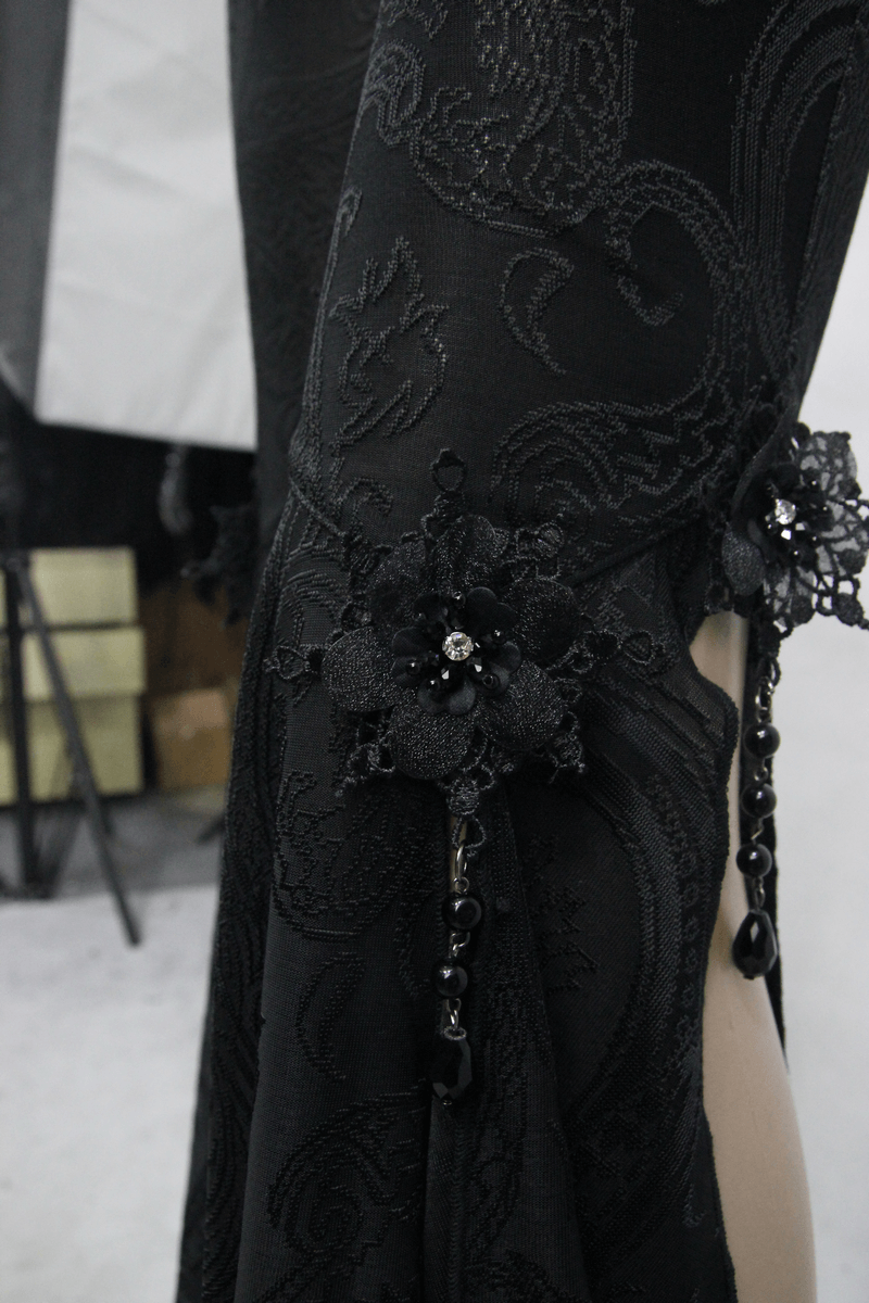 Close-up of black gothic flare pants featuring intricate floral pendants and a slit design for a stylish touch.