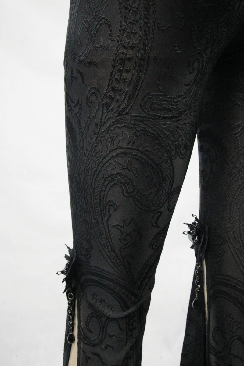 Close-up of black gothic fringe bell-bottom pants with slit details and decorative pendants.