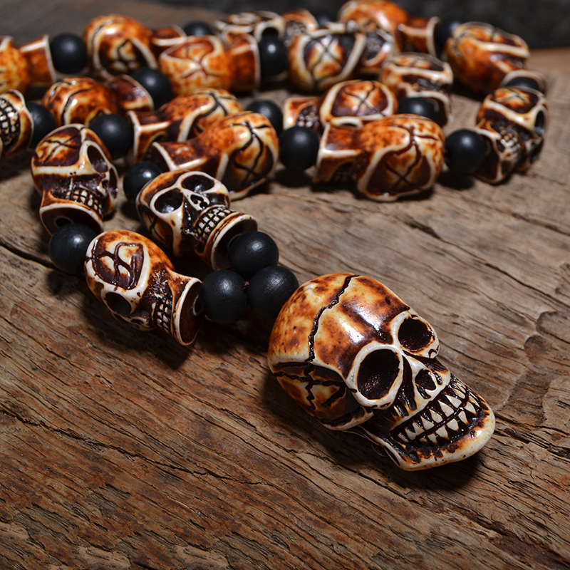 Gothic imitation bone necklace featuring skull-shaped details on a wooden background.