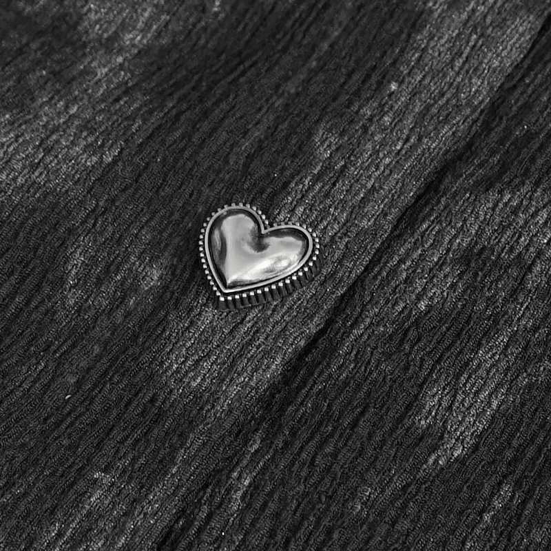 Close-up of a shiny heart-shaped embellishment on textured black fabric.