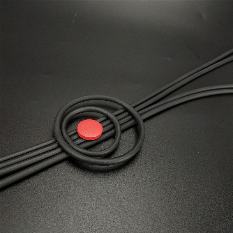 Close-up of black rubber cords organized with a red circular rubber piece, set against a dark background.
