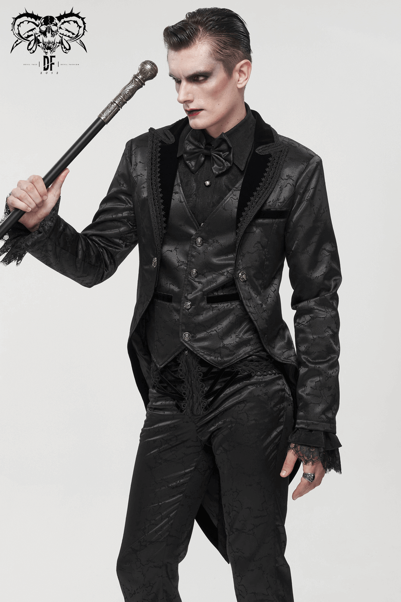 Gothic male model wearing a stylish black two-piece coat with lace and vintage patterns, holding a cane.