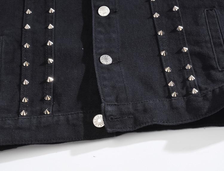Close-up of black denim vest with silver studs, showcasing gothic style and detailed rivet design.