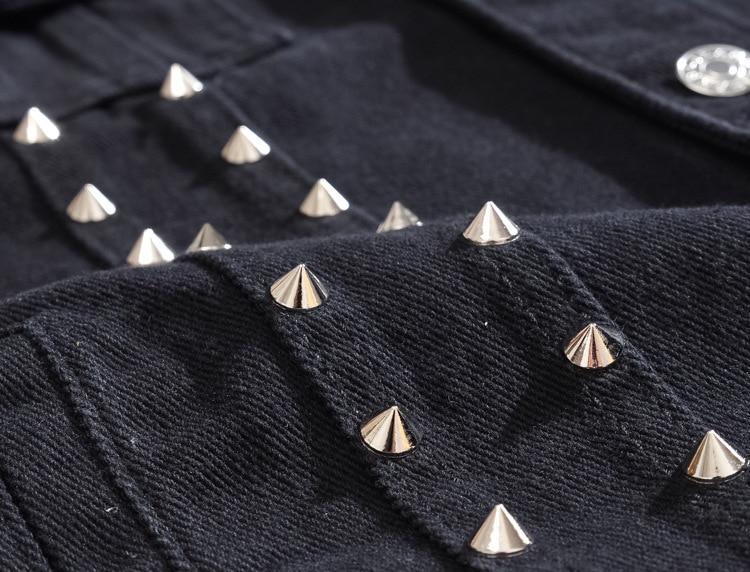 Close-up of gothic men's sleeveless denim vest featuring edgy silver rivets on black fabric for alternative fashion.