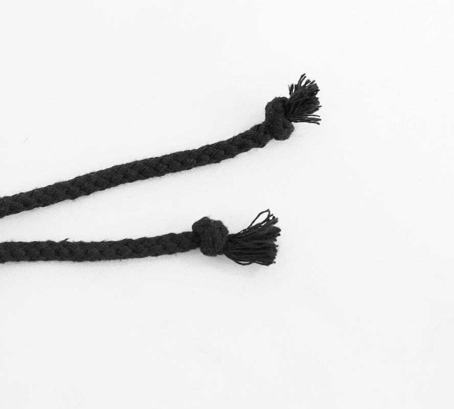 Close-up of black braided tassel ties, perfect for gothic-style clothing and accessories.