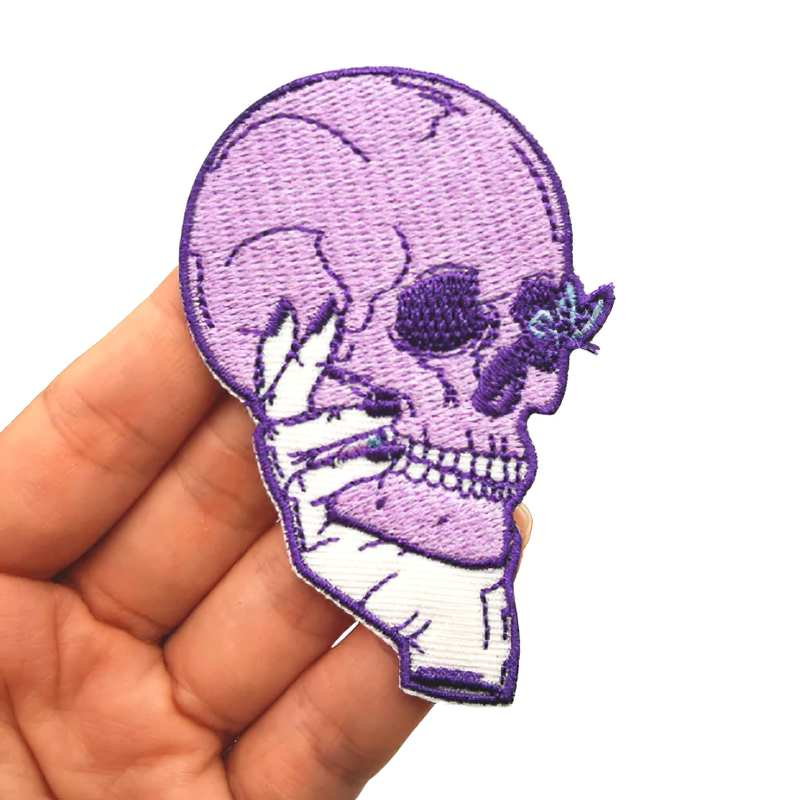 Gothic pink skull patch held in hand, stylish unisex accessory for clothing and decoration.