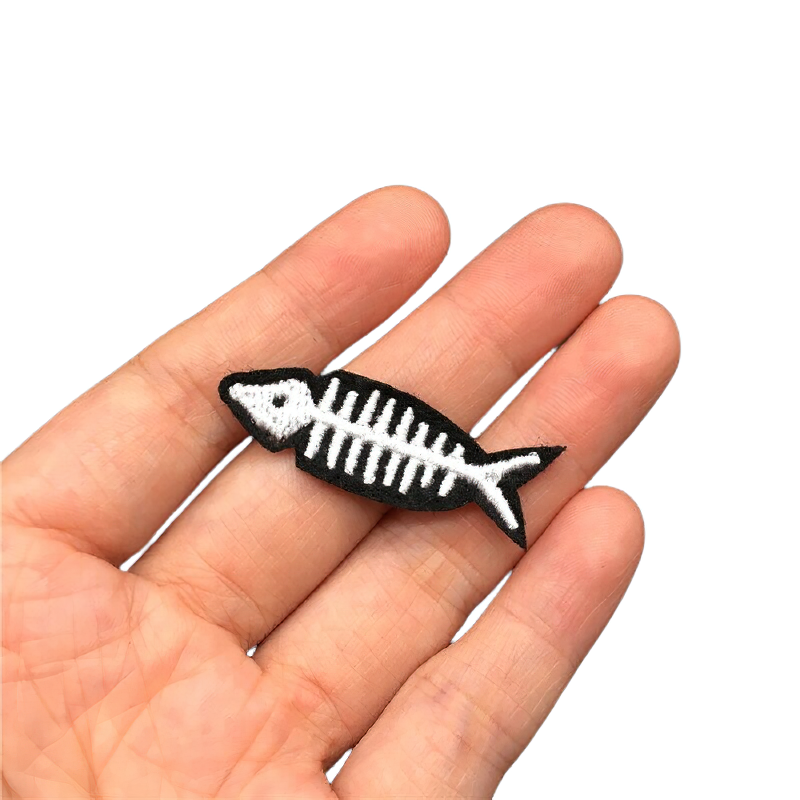 Hand holding a Gothic fish skeleton patch, stylish accessory for casual rock clothing, unisex embroidered badge.