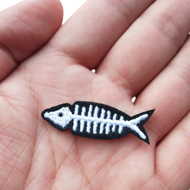 Unisex embroidered fish skeleton patch held in hand, perfect for casual rock style clothing accessories.