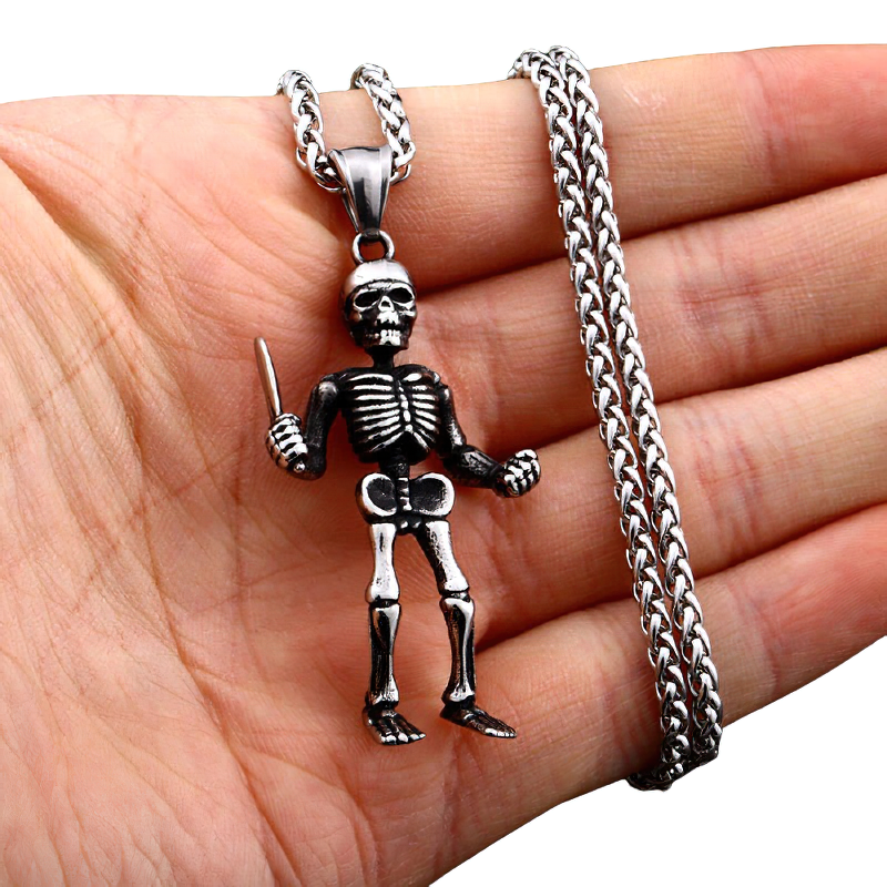 Gothic unisex stainless steel skeleton pendant necklace held in hand, featuring a skull and knife design.