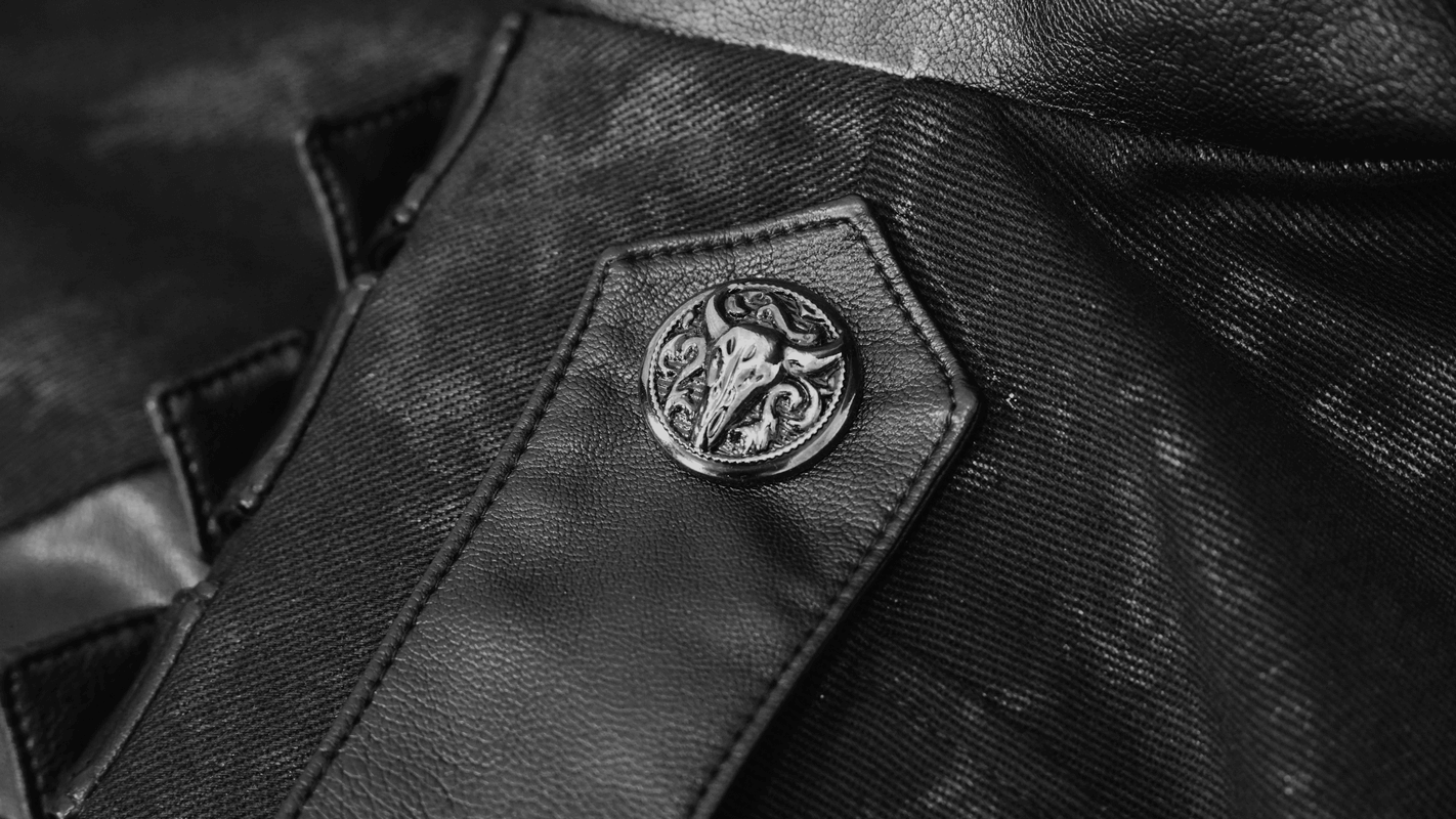 Close-up of a Gothic punk trench coat button with intricate design and black fabric background.