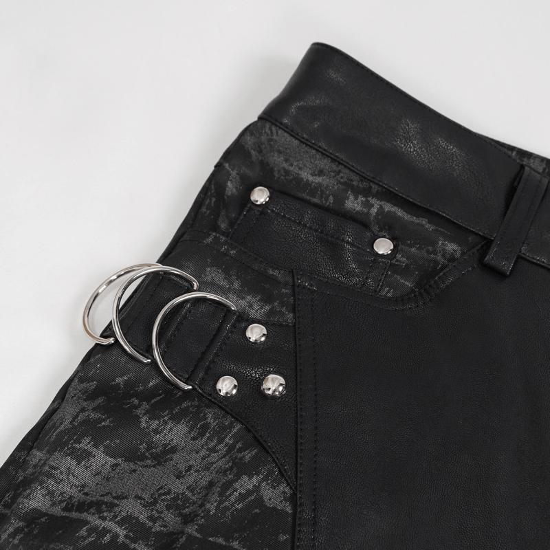 Close-up of stylish black trousers with silver rings and pockets, showcasing punk fashion details.