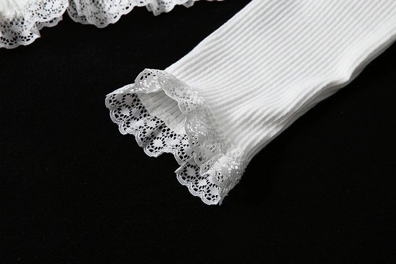 Close-up of white lace-cuffed long sleeve top, featuring feminine details and ribbed texture.