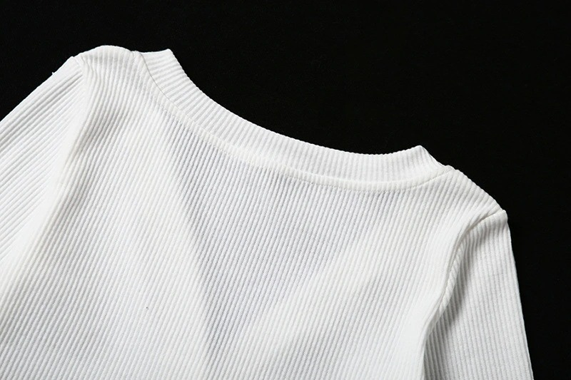 Close-up of a white ribbed long sleeve top, highlighting its elegant neckline and soft texture.
