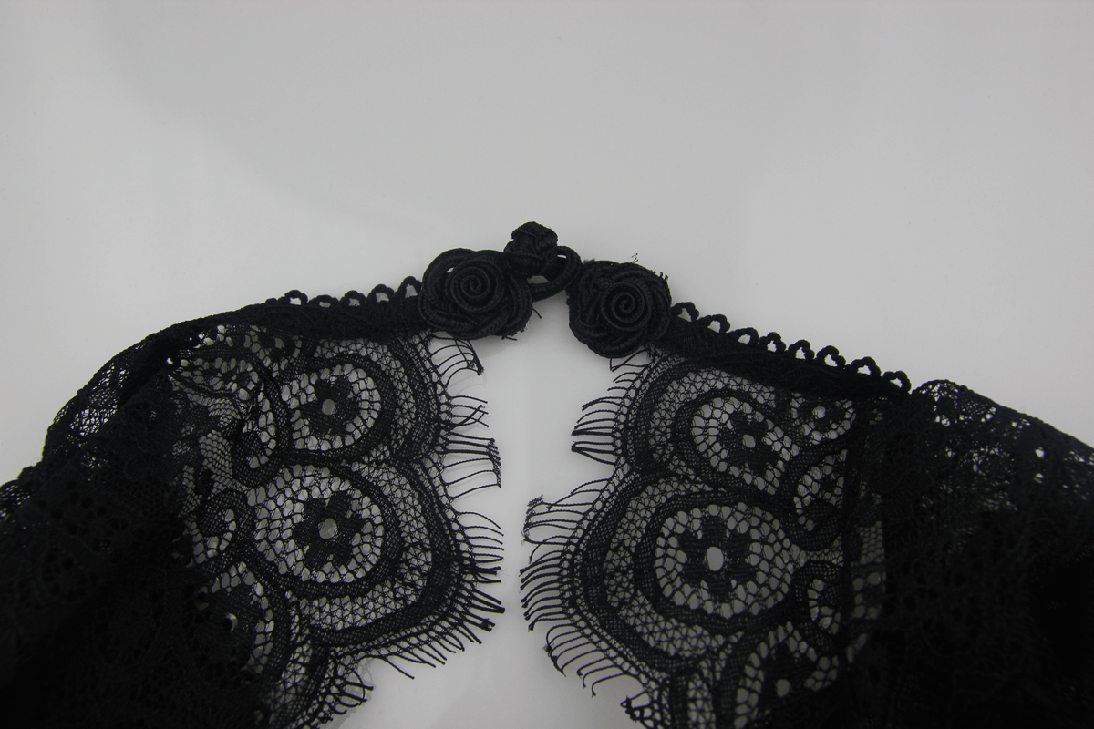 Close-up of lace details and floral rosette buttons on a gothic dress, showcasing intricate design elements.